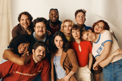 The SNL cast posing in front of a cream backdrop.