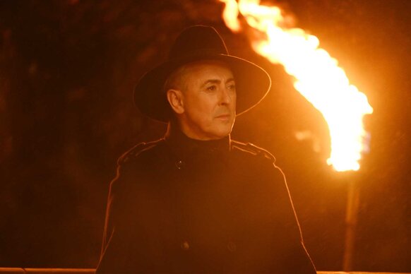 Alan Cumming holding a stick of fire on The Traitors Season 4 Episode 6.