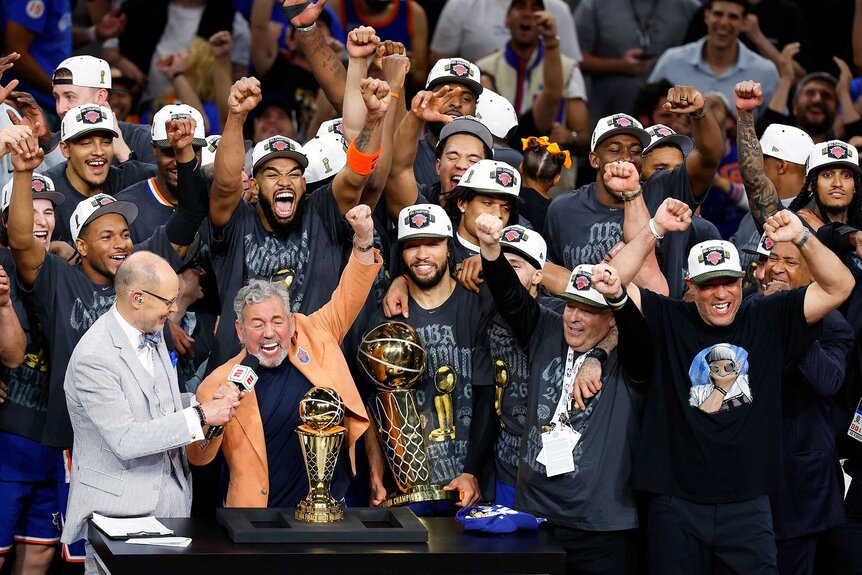 New York Knicks cheering while owner James Dolan is interviewed by Ernie Johnson Jr. after his team's victory against the San Antonio Spurs in Game Five of the 2026 NBA Finals.
